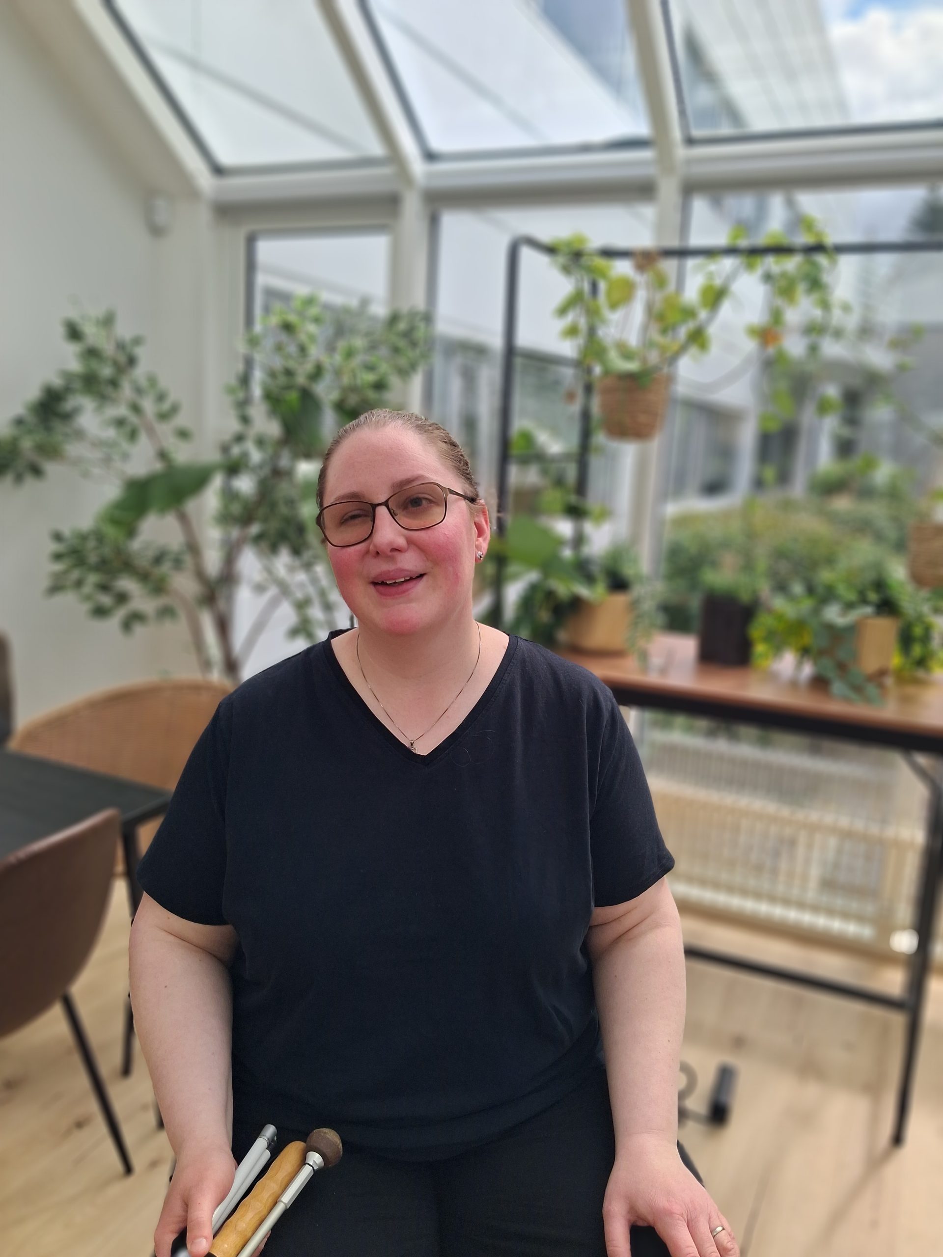 Uppstillt mynd af Söndru Dögg sem situr í glerskála og sést í plöntur